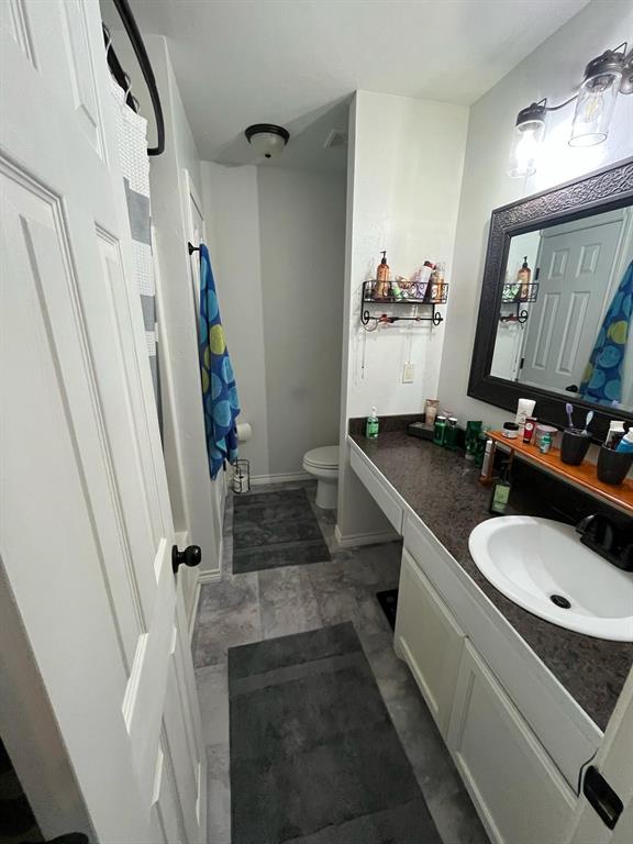 bathroom with toilet, baseboards, shower / tub combo with curtain, and vanity