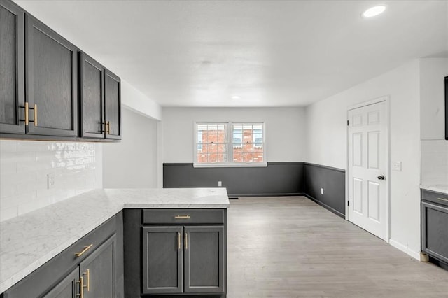 10313 N Mckinley Ave, Oklahoma City, OK 73114 - kitchen featuring light stone counters, a peninsula, light wood-style floors, decorative backsplash, and recessed lighting
