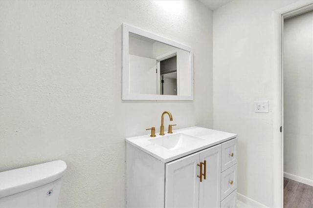 10313 N Mckinley Ave, Oklahoma City, OK 73114 - half bathroom featuring toilet, vanity, baseboards, and wood finished floors