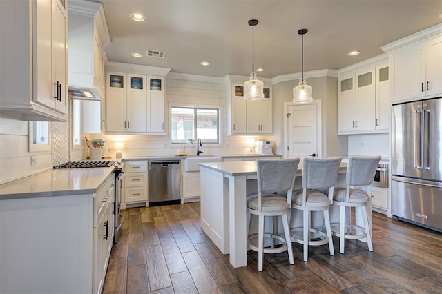 kitchen with visible vents, backsplash, stainless steel appliances, white cabinetry, and a sink