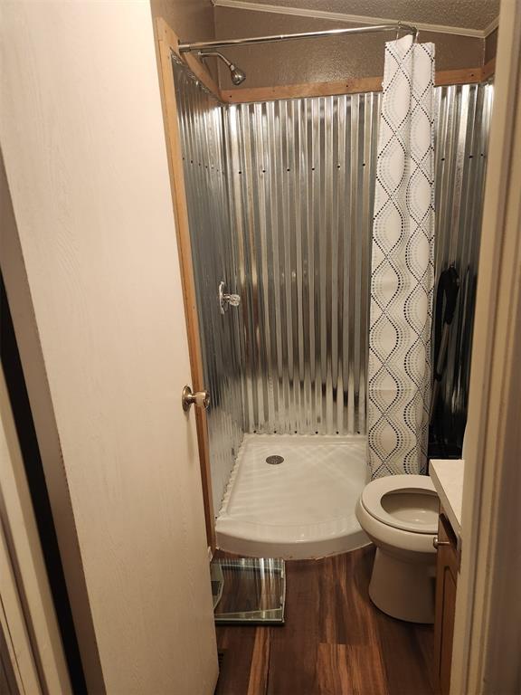 full bathroom with a stall shower, vanity, toilet, and wood finished floors