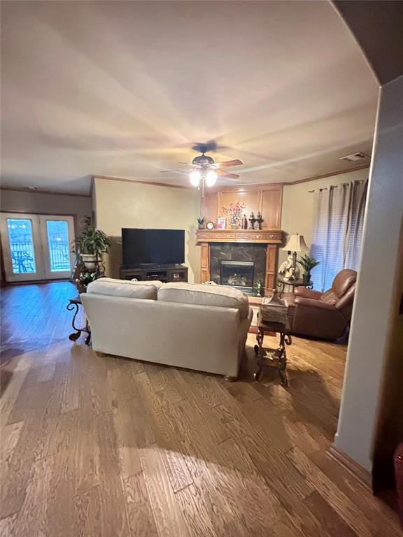 living area featuring a fireplace, wood finished floors, and ceiling fan