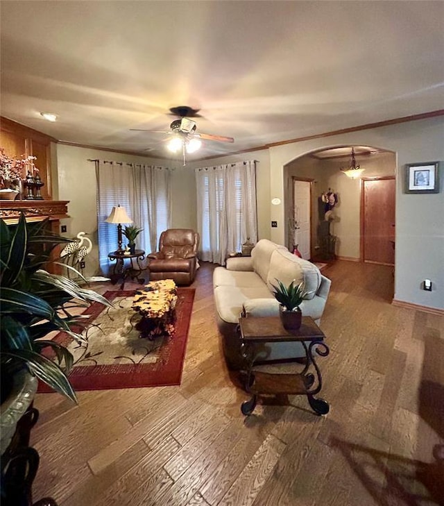 living room featuring arched walkways, crown molding, ceiling fan, and wood finished floors