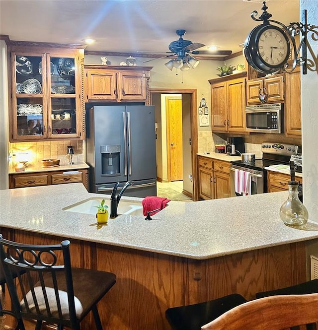 kitchen with brown cabinets, appliances with stainless steel finishes, a kitchen breakfast bar, and a sink