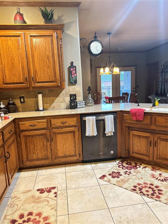 kitchen featuring brown cabinets, stainless steel dishwasher, and light countertops