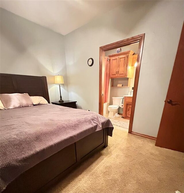 bedroom featuring ensuite bathroom and light carpet