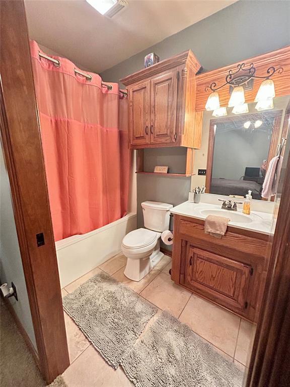 full bathroom with tile patterned floors, toilet, vanity, and shower / bath combination with curtain