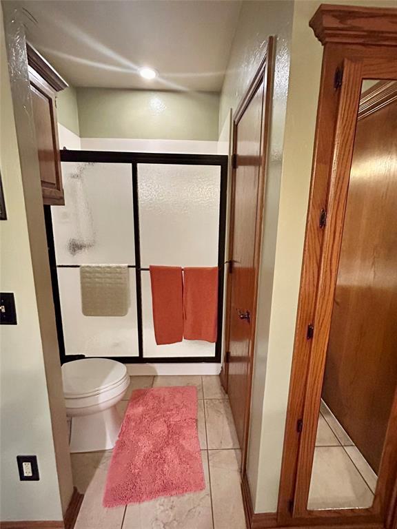 full bathroom featuring tile patterned floors, toilet, and a shower stall