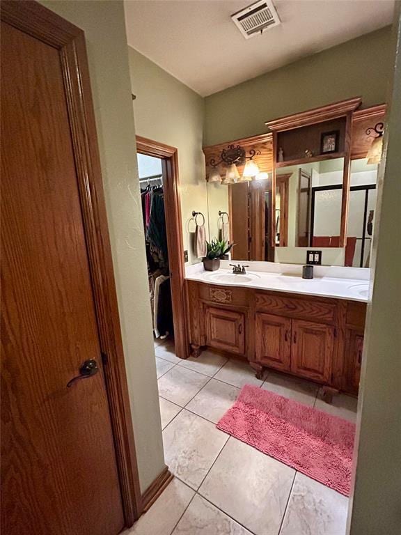 bathroom featuring tile patterned floors, visible vents, a sink, double vanity, and a spacious closet