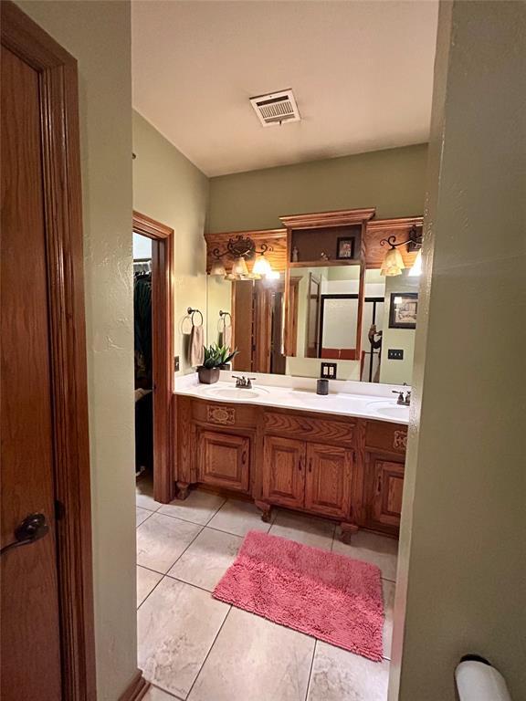 full bath featuring a sink, visible vents, double vanity, and tile patterned flooring