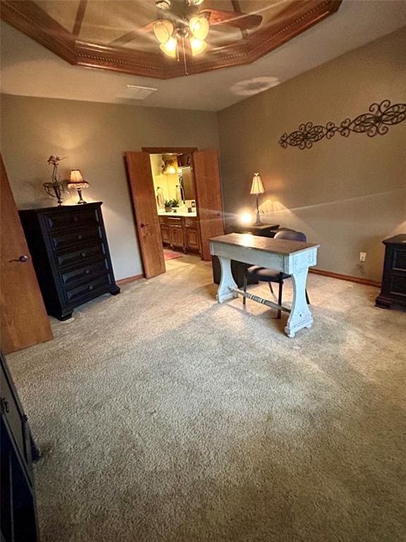 office area with baseboards, ceiling fan, light carpet, a wood stove, and a raised ceiling