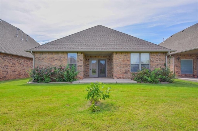 rear view of property featuring a yard, a patio, brick siding, and french doors