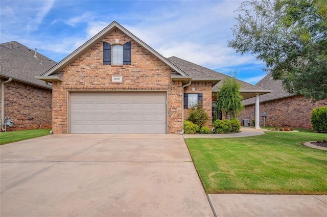 10931 Silo Ridge Rd, Oklahoma City, OK 73170 - view of front of home featuring concrete driveway, brick siding, a front yard, and cooling unit