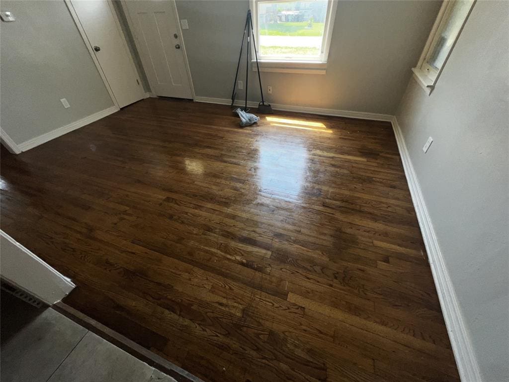 unfurnished room with dark wood-type flooring and baseboards