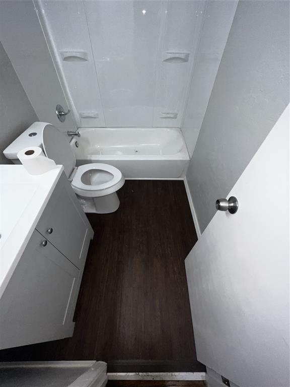 bathroom with toilet, shower / tub combination, wood finished floors, and vanity