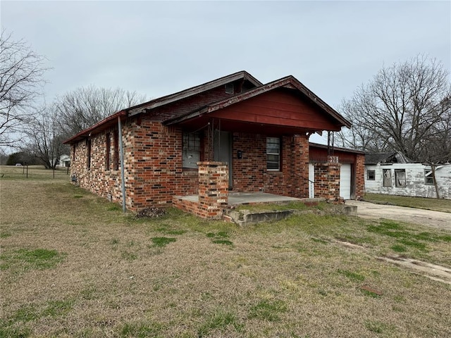 view of front of home featuring a garage, concrete driveway, a front lawn, and brick siding