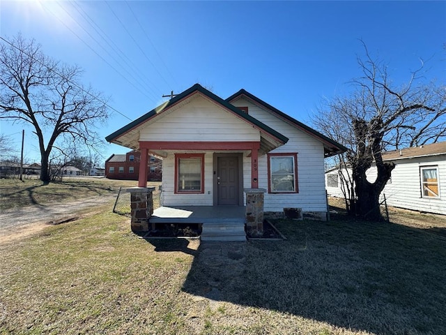 bungalow with covered porch and a front lawn