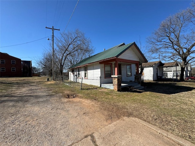 view of side of home featuring metal roof and a lawn