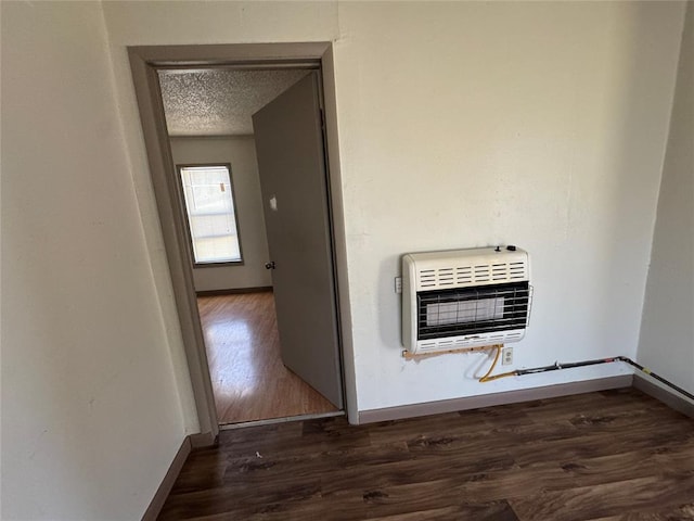 interior space with heating unit, baseboards, a textured ceiling, and wood finished floors