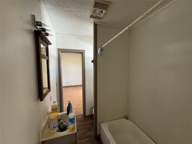 full bath featuring tub / shower combination, visible vents, a textured ceiling, and wood finished floors