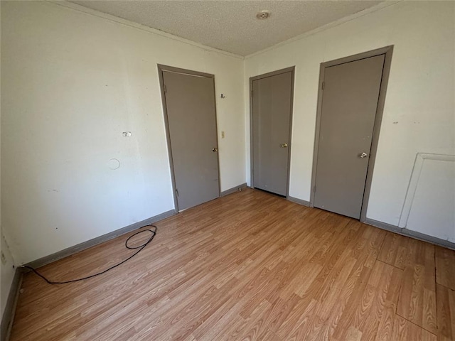 unfurnished bedroom featuring light wood-style flooring, baseboards, and a textured ceiling