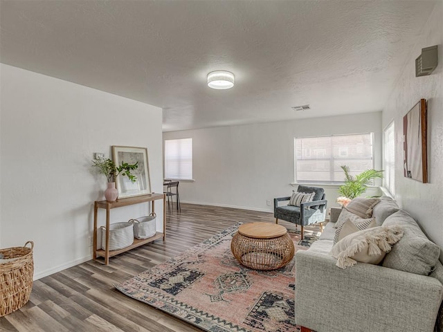 living room with a wealth of natural light, wood finished floors, and visible vents