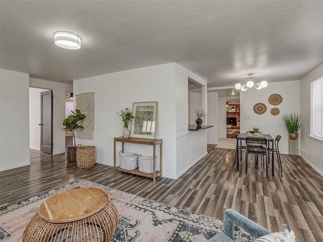 interior space featuring a notable chandelier, a textured ceiling, baseboards, and wood finished floors