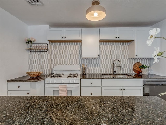 kitchen featuring white gas stove, a sink, visible vents, white cabinets, and dark stone countertops