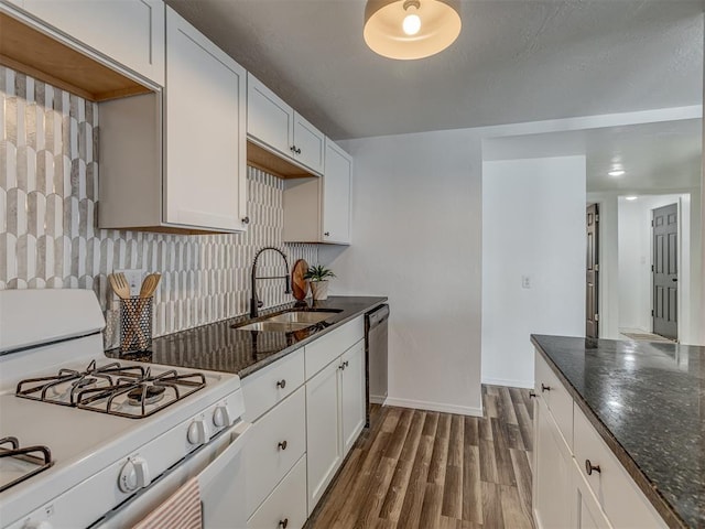 kitchen featuring dark wood-style floors, decorative backsplash, stainless steel dishwasher, a sink, and white gas range oven