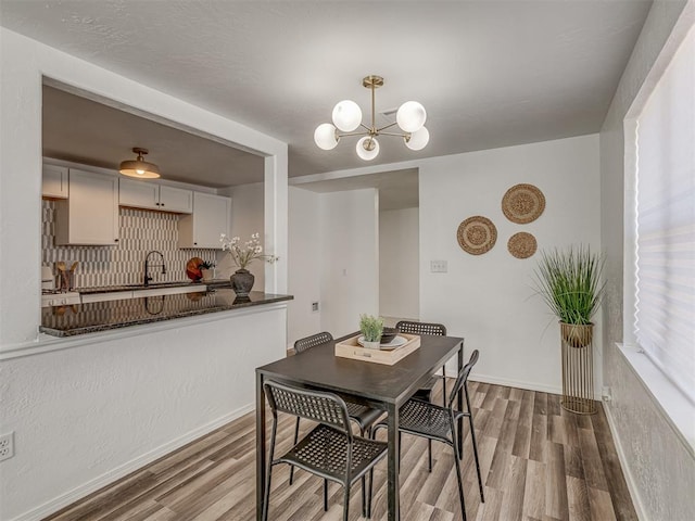 dining space featuring a notable chandelier, baseboards, and wood finished floors