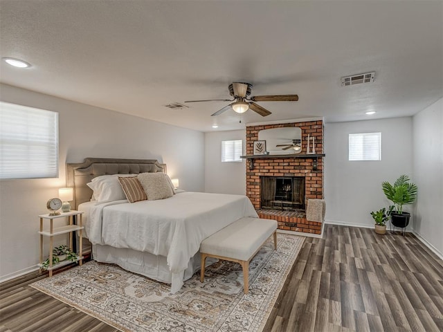 bedroom featuring a brick fireplace, baseboards, visible vents, and wood finished floors