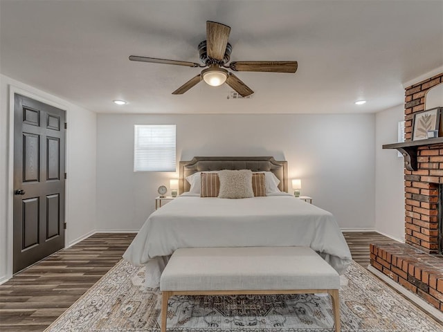 bedroom with a fireplace, recessed lighting, dark wood-type flooring, a ceiling fan, and baseboards