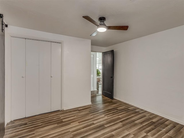 unfurnished bedroom with a ceiling fan, a closet, baseboards, and wood finished floors