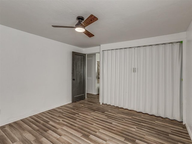 unfurnished bedroom with a ceiling fan, baseboards, and wood finished floors