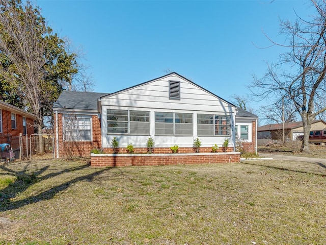 rear view of house featuring a yard, brick siding, fence, and a sunroom