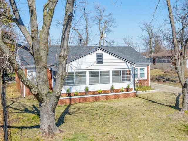 view of front of home featuring a sunroom, a front lawn, and roof with shingles