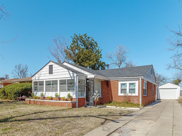 view of front of property featuring an outbuilding, a garage, brick siding, driveway, and a front lawn