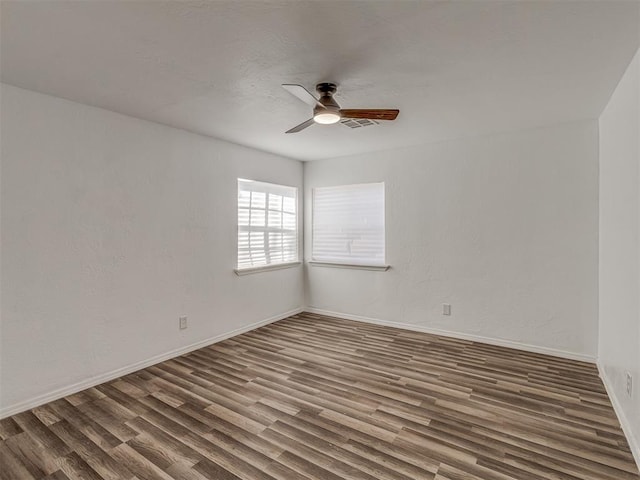 unfurnished room with a ceiling fan, visible vents, baseboards, and wood finished floors