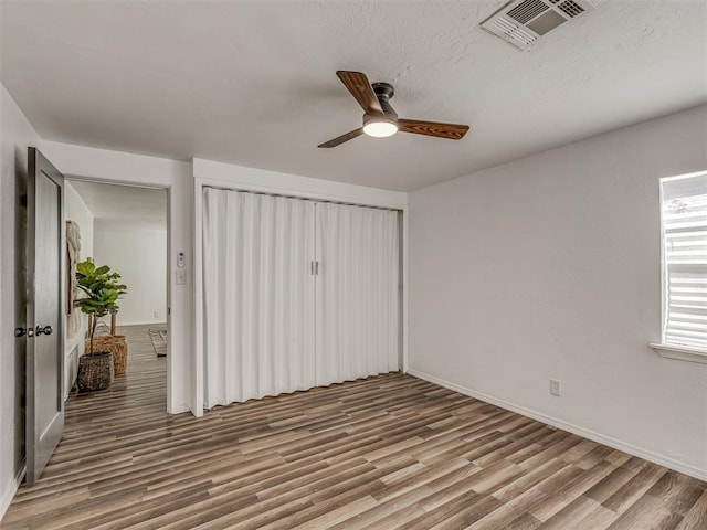 unfurnished bedroom with a closet, visible vents, baseboards, and wood finished floors