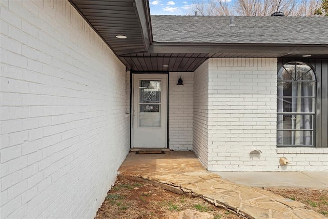 view of exterior entry with a shingled roof