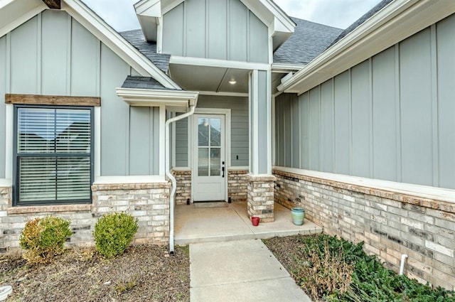 entrance to property with stone siding, board and batten siding, and a shingled roof