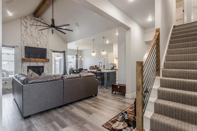 living room featuring stairway, high vaulted ceiling, beamed ceiling, and light wood finished floors