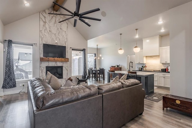 living room with beam ceiling, a premium fireplace, wood finished floors, and high vaulted ceiling