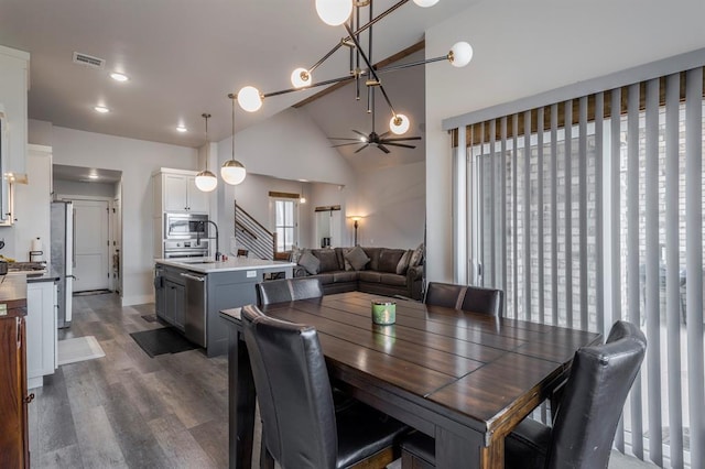 dining area with visible vents, high vaulted ceiling, dark wood-style flooring, ceiling fan, and stairs