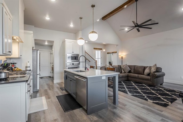 kitchen with light wood-type flooring, beam ceiling, appliances with stainless steel finishes, and open floor plan