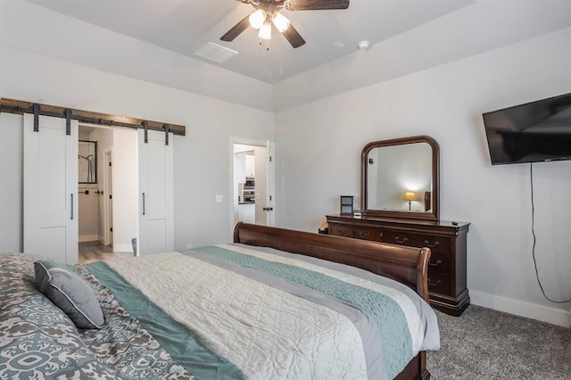 carpeted bedroom with a barn door, baseboards, visible vents, and ceiling fan