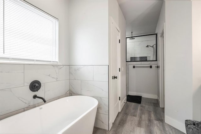 full bath with tile walls, a soaking tub, walk in shower, and wood finished floors