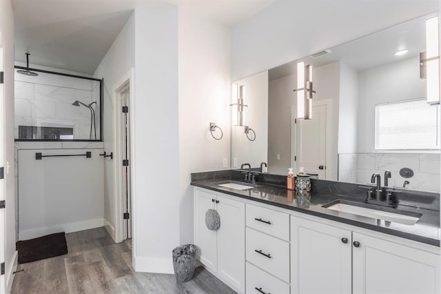 bathroom featuring double vanity, walk in shower, wood finished floors, and a sink