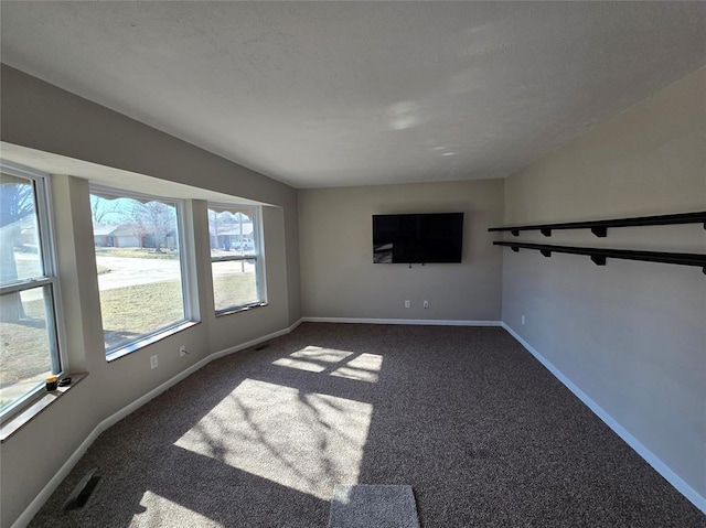 spare room featuring visible vents, baseboards, and dark colored carpet