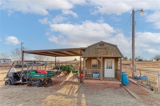 view of outbuilding with a detached carport, fence, and an outbuilding